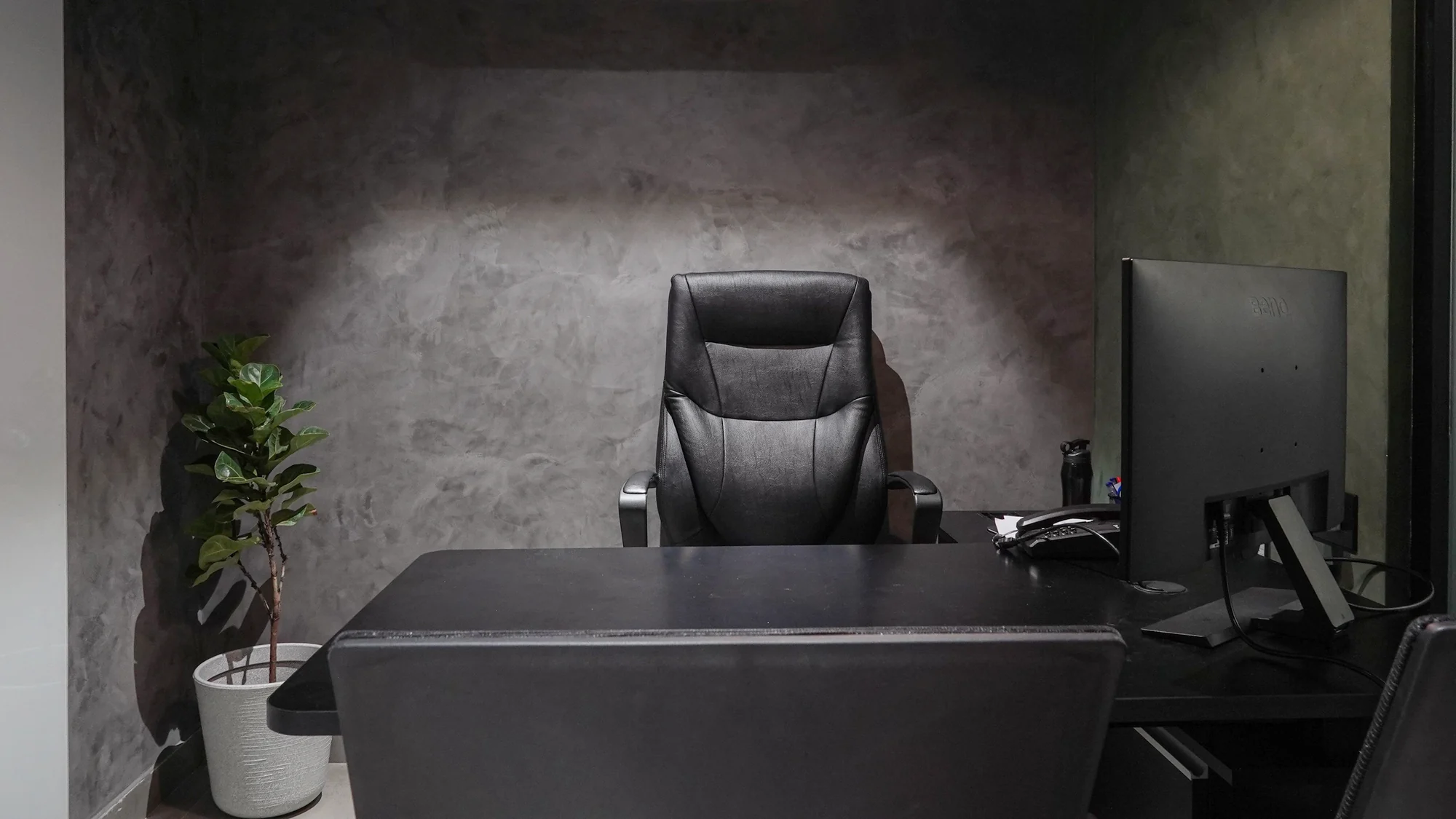 An unoccupied office, the desk chair empty and the monitor switched off